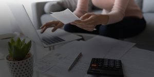 Person adding up bills at table with calculator