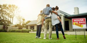 family standing in front of new home with sold sign